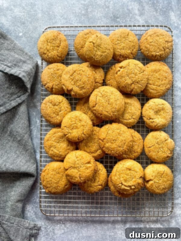 Chewy Brown Sugar Delights 10 Flattened cookie dough balls on a baking sheet, with additional sugar crystals sprinkled on top, ready for the oven.