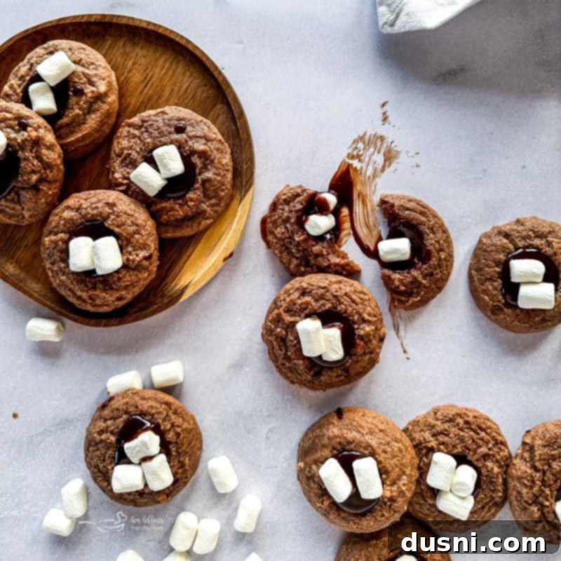 Hot Cocoa Thumbprint Delights 3 Close-up of Hot Chocolate Thumbprints Cookies on a cooling rack, showing their fudgy centers and marshmallow topping.