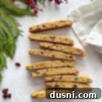 Holiday biscotti on a white surface with pine tree and berries around it.