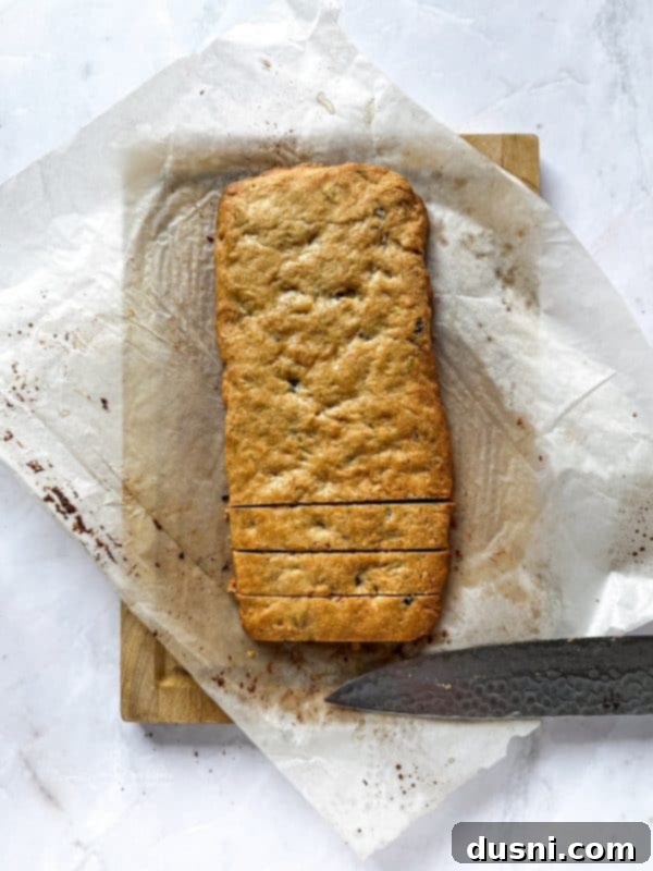 Baked biscotti log, golden brown, on a baking sheet.