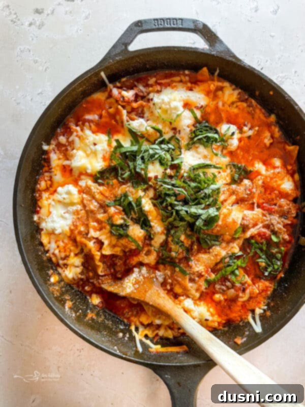 Lazy Slow Cooker Ravioli Lasagna 4 Skillet Lasagna being served from a large skillet.