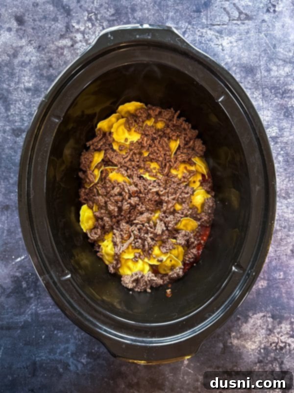 Lazy Slow Cooker Ravioli Lasagna 9 Step 4: Layering half of the frozen ravioli, ground beef, and mozzarella cheese.