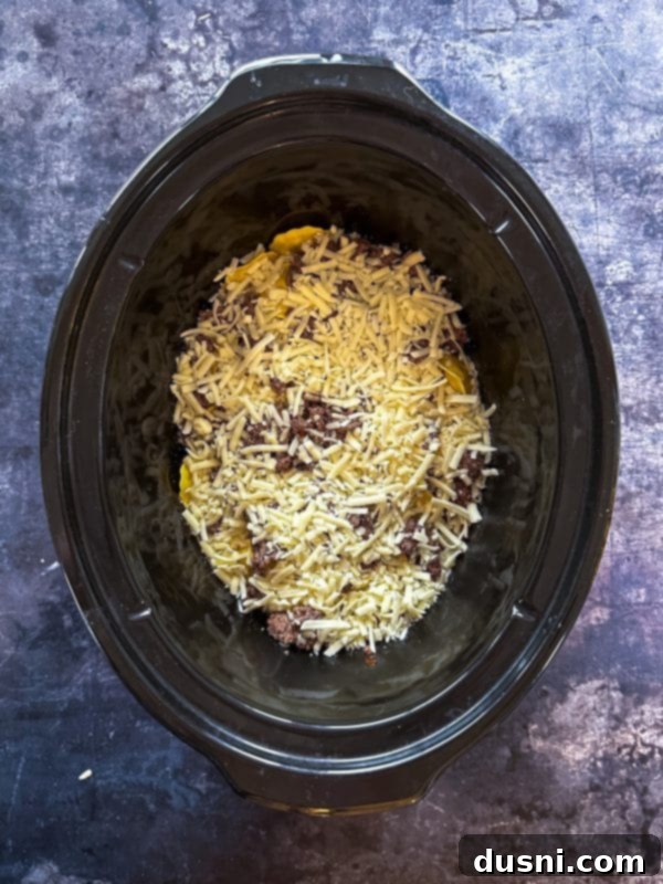 Lazy Slow Cooker Ravioli Lasagna 10 Step 5: Repeating the layers with remaining sauce, ravioli, beef, and cheese.