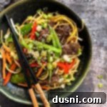 Savory Beef Lo Mein 17 Close up of Chops sticks atop the Beef Lo Mein in a dark green bowl.