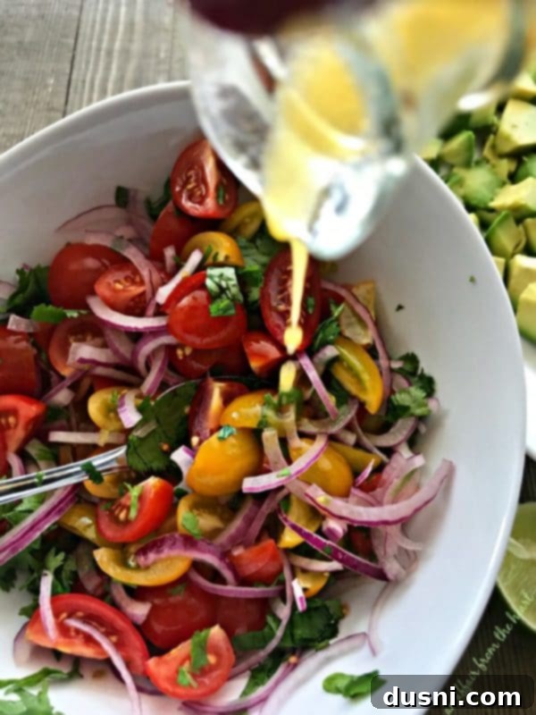 Prepared sliced tomatoes, red onion, and chopped cilantro in a mixing bowl, ready to be dressed.