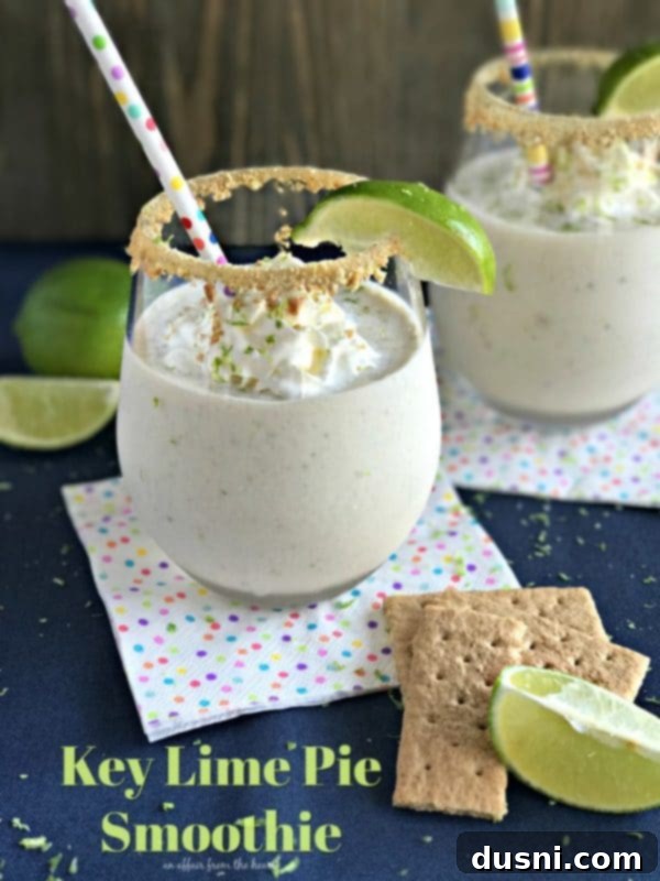 Zesty Key Lime Delight 2 Key Lime Pie Smoothie in a tall glass, garnished with whipped cream, lime zest, and graham cracker crumbs.