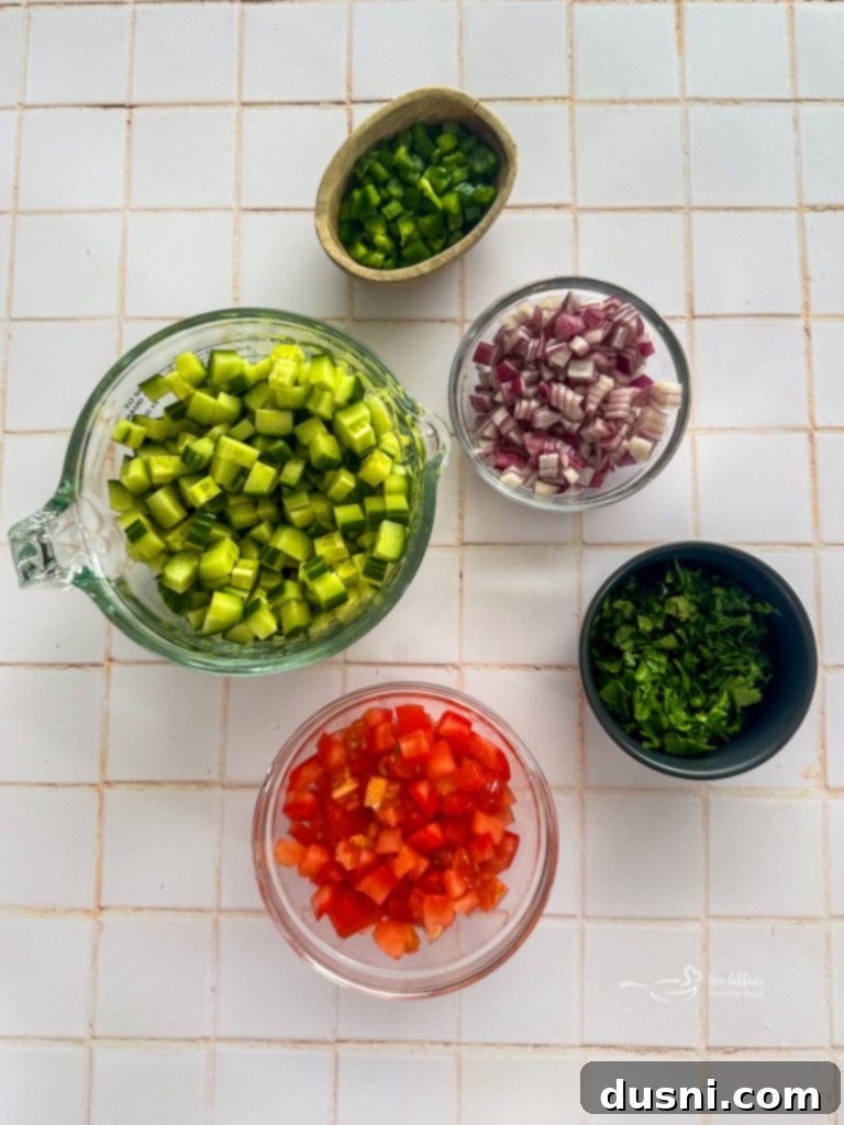 A bowl of freshly chopped cucumbers, tomatoes, and onions.