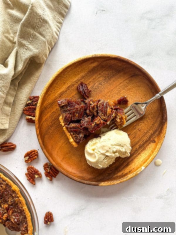 A slice of golden pecan pie on a white plate with a fork beside it.