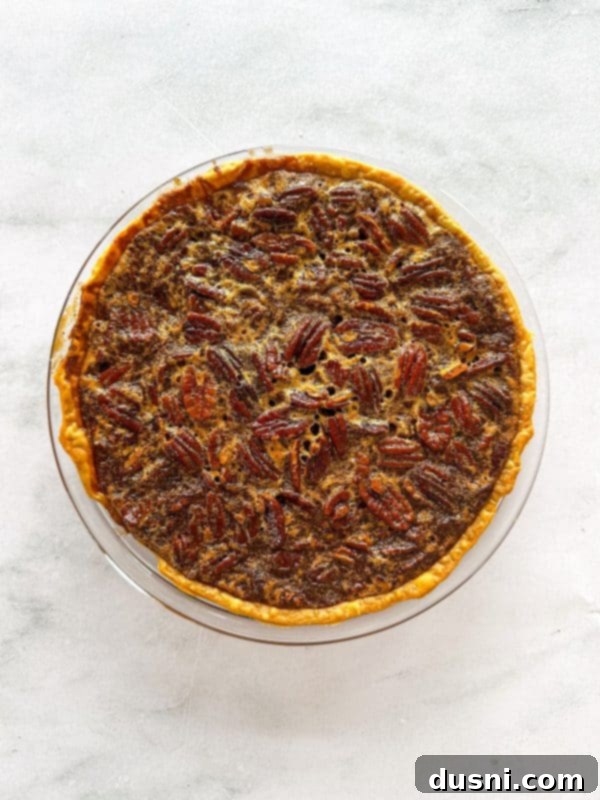 A baked pecan pie cooling on a wire rack.