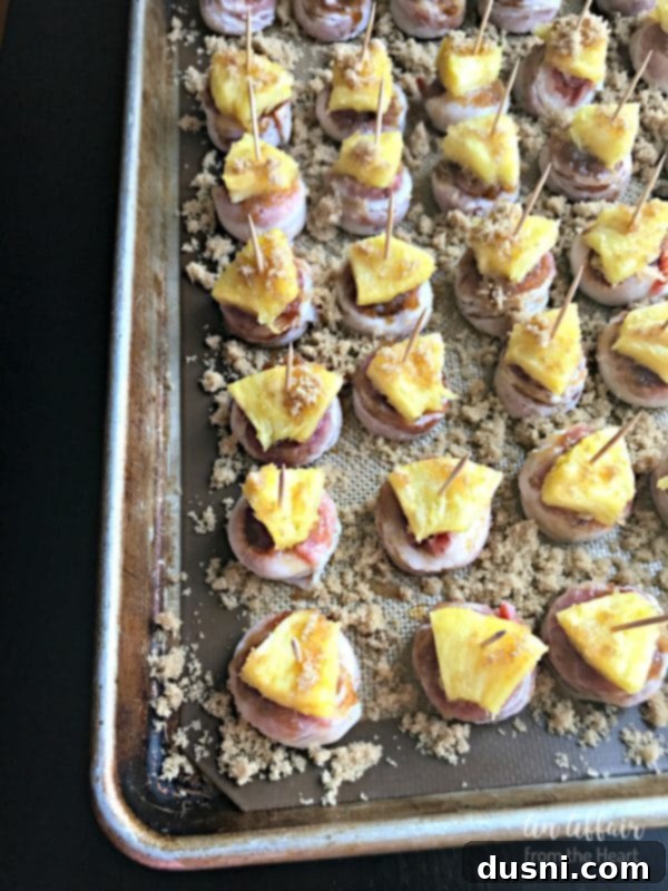 Aloha Bacon Wrapped Sausage Poppers 11 Pineapple slices being added to Aloha Bacon Wrapped Sausage Bites, secured with toothpicks