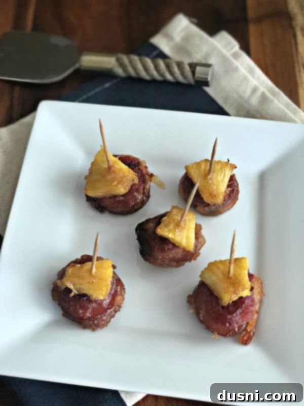 Aloha Bacon Wrapped Sausage Poppers 5 Hand holding an Aloha Bacon Wrapped Sausage Bite