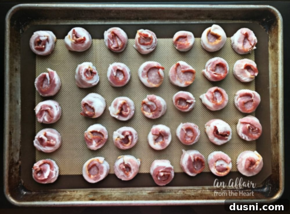 Aloha Bacon Wrapped Sausage Poppers 9 Bacon-wrapped sausage bites on a baking sheet lined with Silpat