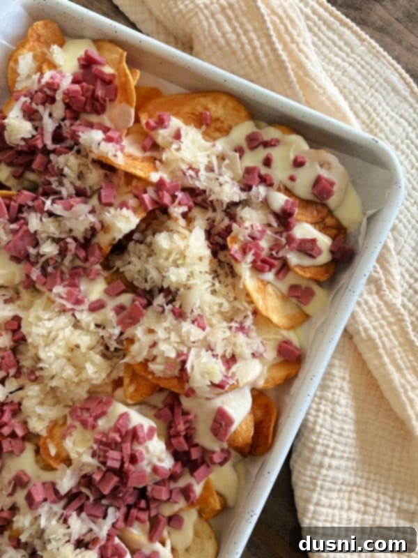 Loaded Reuben Nachos 10 Tangy Frank's Kraut being added on top of the corned beef and cheese
