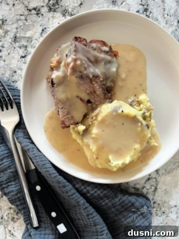 Perfectly roasted pork shoulder with a rich brown crust, surrounded by homemade gravy in a roasting pan, ready to be served for a hearty family meal.