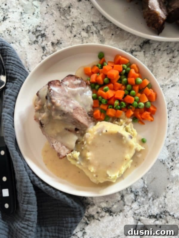A close-up of tender, shredded pork roast, glistening with rich gravy, ready to be served or added to sandwiches.
