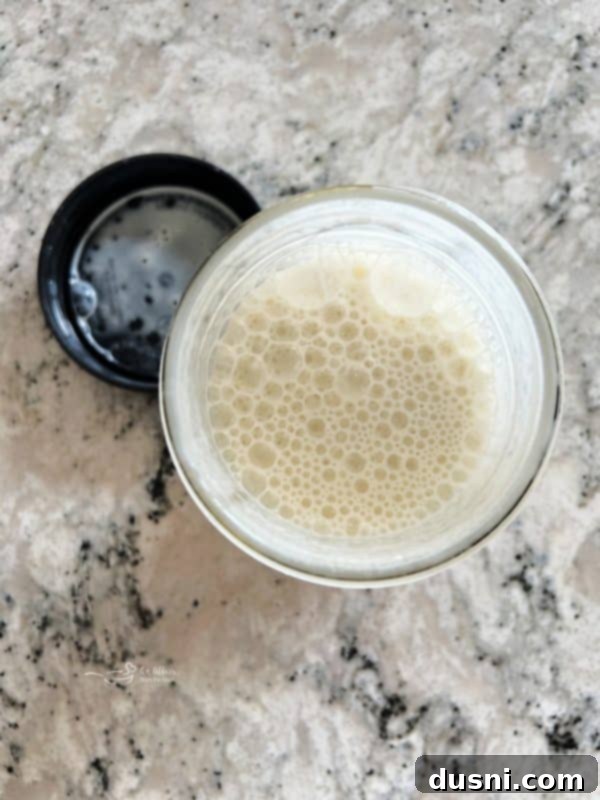 A cook preparing a milk and flour slurry in a glass jar, which will be used to thicken the homemade gravy.