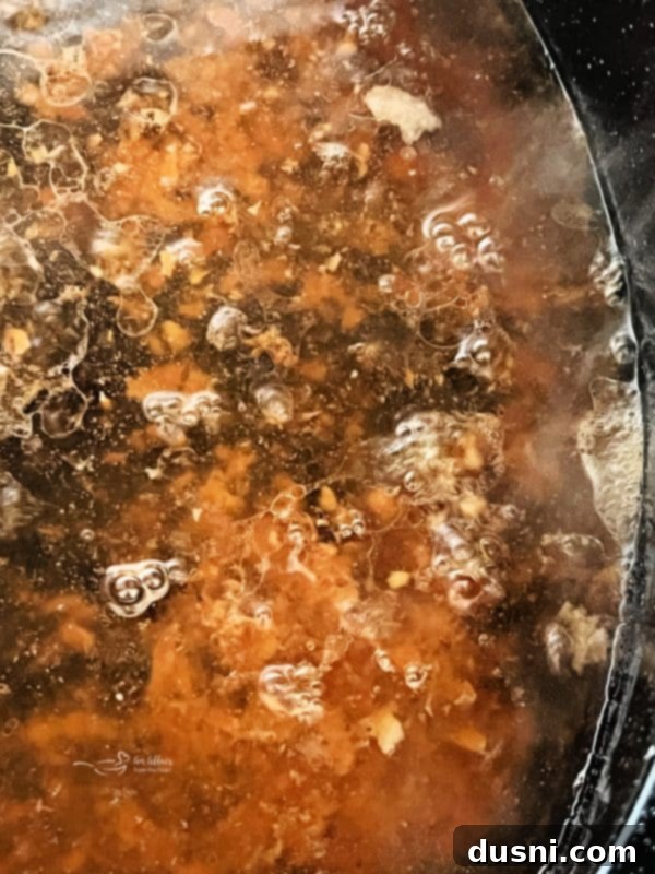 A roasting pan filled with rich pork drippings on a stovetop burner, preparing to make homemade gravy.