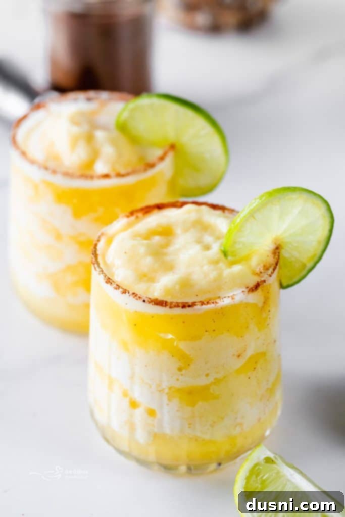 Overhead shot of two Frozen Pineapple Margaritas with a pitcher in the background, ready for a party.
