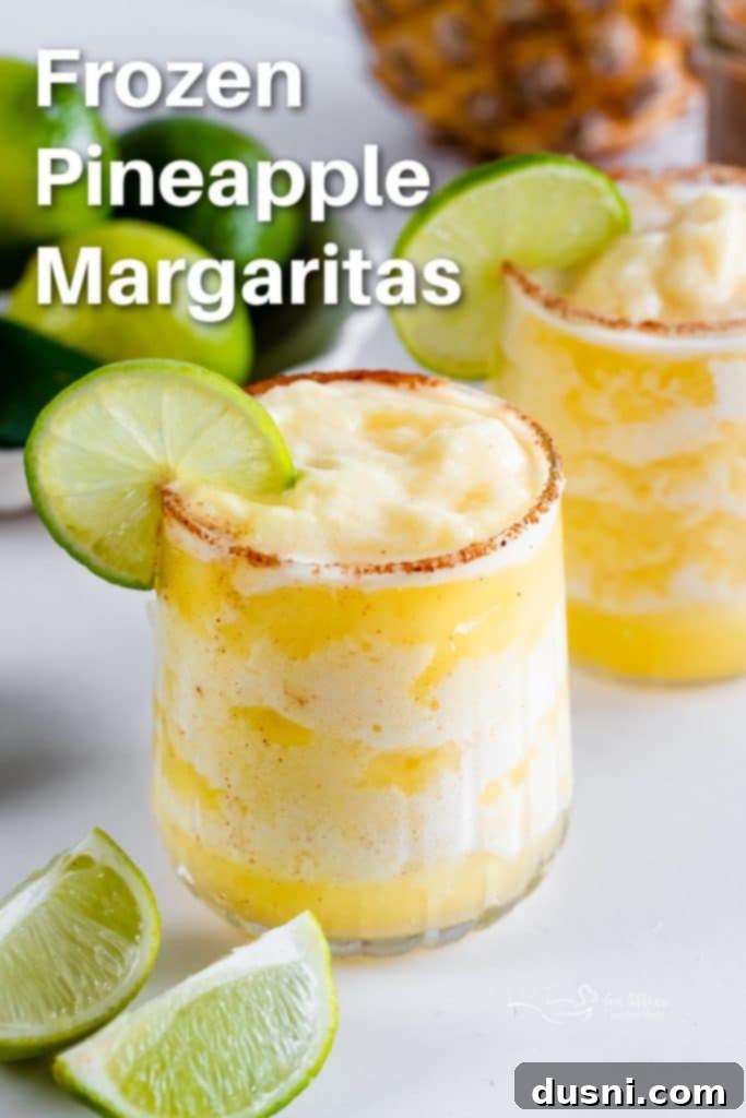 A stunning hero shot of a perfectly blended Frozen Pineapple Margarita in a salt-rimmed glass, garnished with lime.