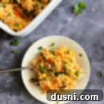 Dorothy's Golden Cheesy Vegetable Rice Bake 18 Cheesy Vegetable Rice Bake on a white plate with a fork.