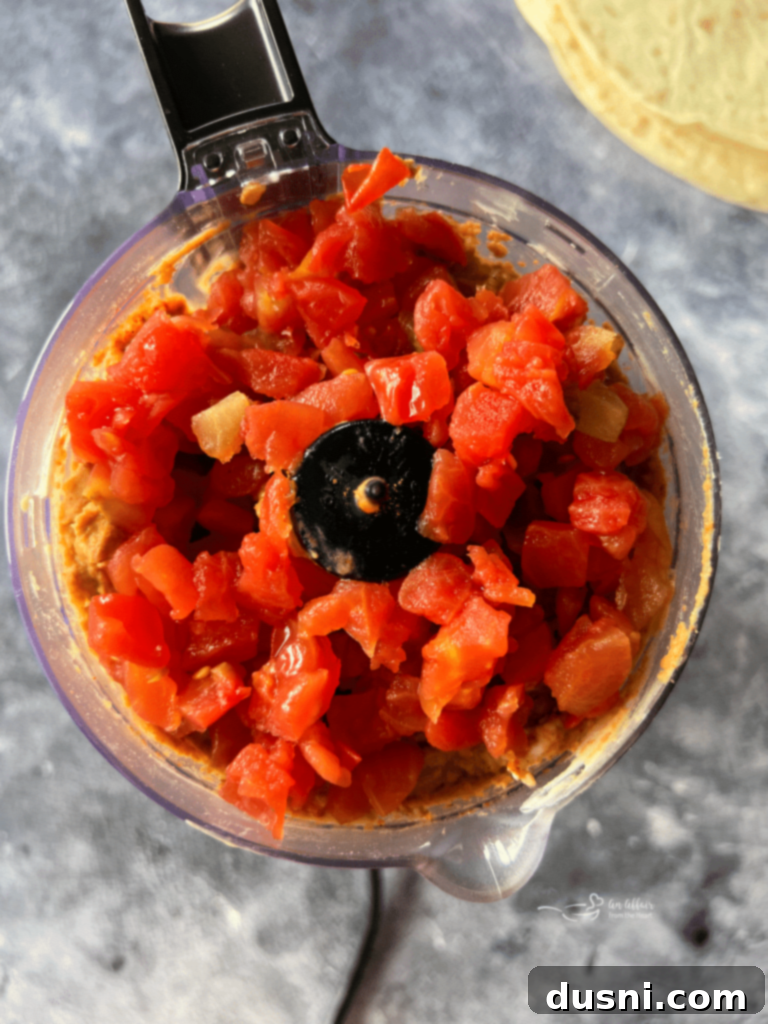 Food processor blending bean salad, cream cheese, and taco seasoning