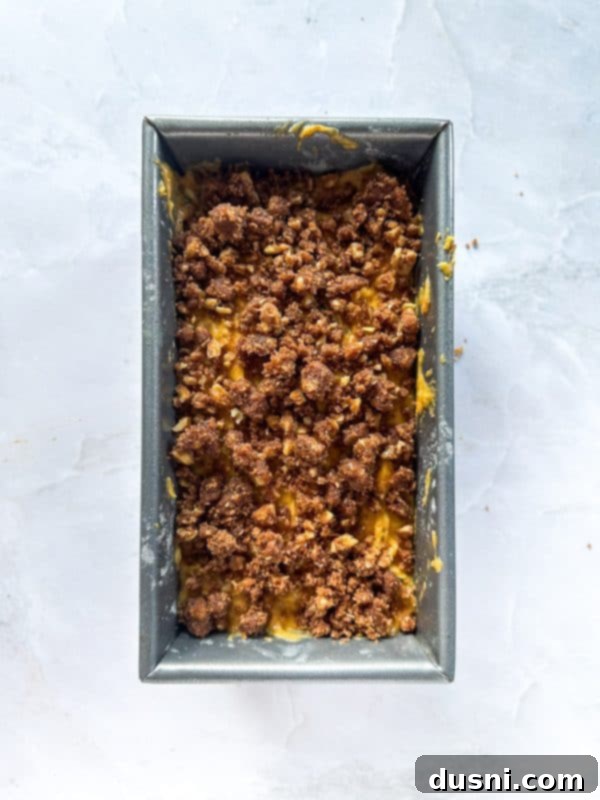 Pumpkin Patch Zucchini Crumble Loaf 12 Streusel topping being sprinkled over the bread batter in loaf pans.