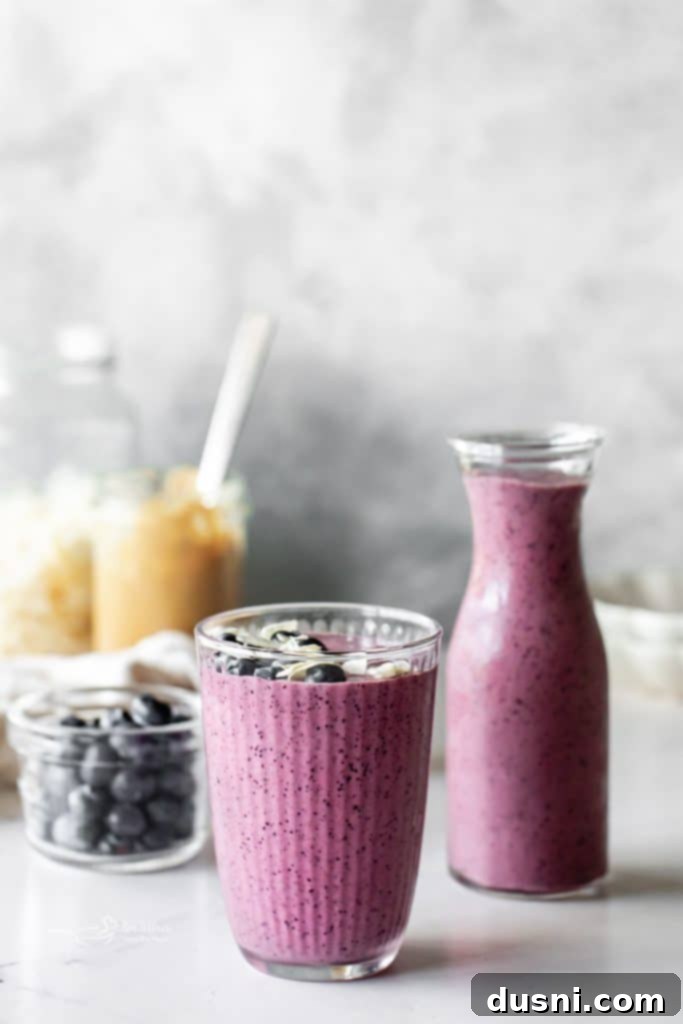Vibrant Blueberry Pineapple Refresher 3 Two glasses of Blueberry Pineapple Smoothie on a wooden cutting board with scattered fruit.