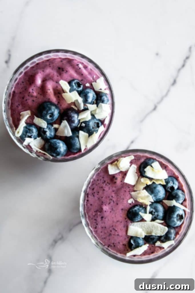 Vibrant Blueberry Pineapple Refresher 4 A glass of Blueberry Pineapple Smoothie garnished with fresh blueberries and a pineapple slice.