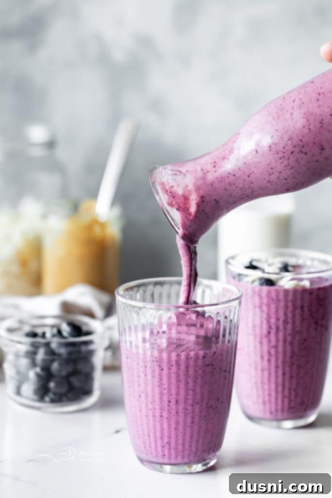 Vibrant Blueberry Pineapple Refresher 5 Close-up of a glass of Blueberry Pineapple Smoothie with a straw, garnished with fresh fruit.
