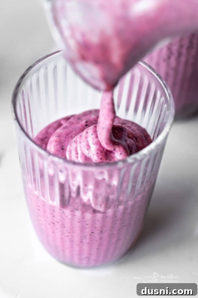 Vibrant Blueberry Pineapple Refresher 9 A Blueberry Pineapple Smoothie garnished with a pineapple slice and blueberries, in a rustic setting.