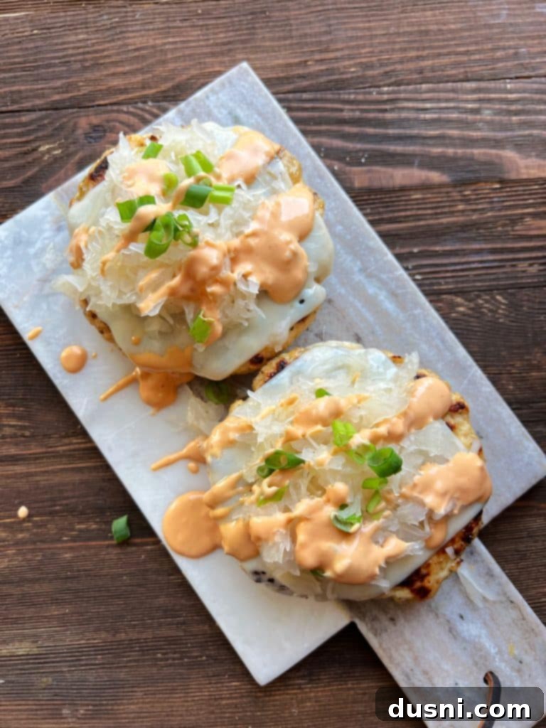 A turkey burger patty on a bun, topped with melted Swiss cheese and a mound of Frank's Kraut.