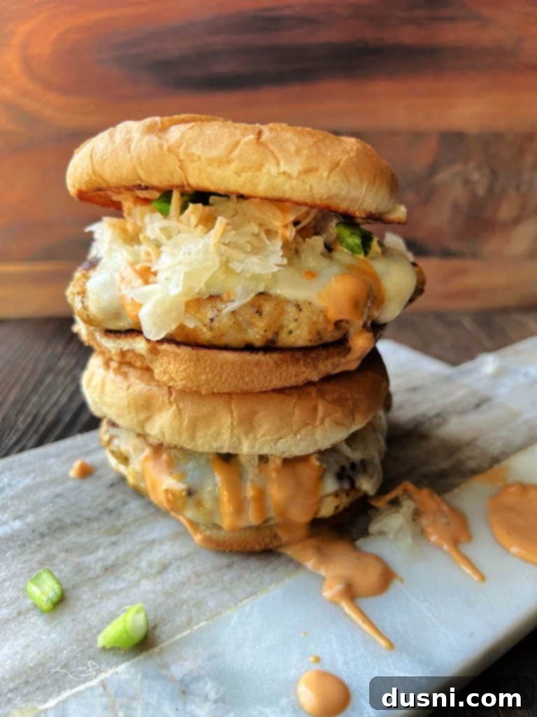Three fully assembled Turkey Reuben Burgers on a wooden board, ready to be served.