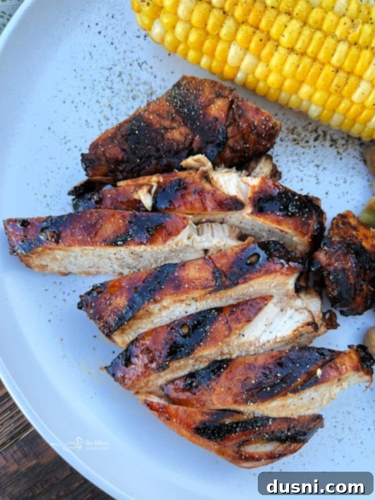 Platter of sliced sweet and smoky grilled chicken with corn on the cob.