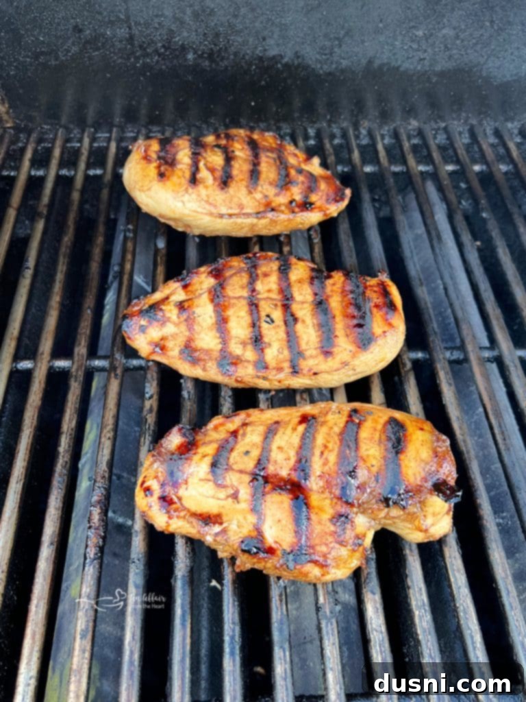 Chicken breasts cooking on a grill.