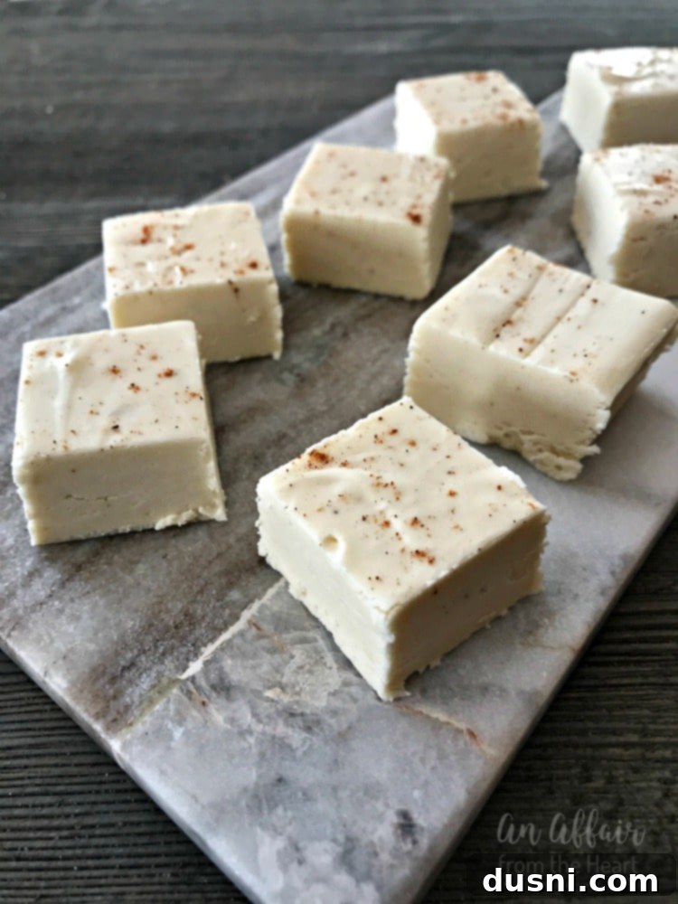 Yuletide Eggnog Bliss 2 A stack of creamy eggnog fudge pieces with nutmeg dusting on a festive holiday background, perfect for Christmas.