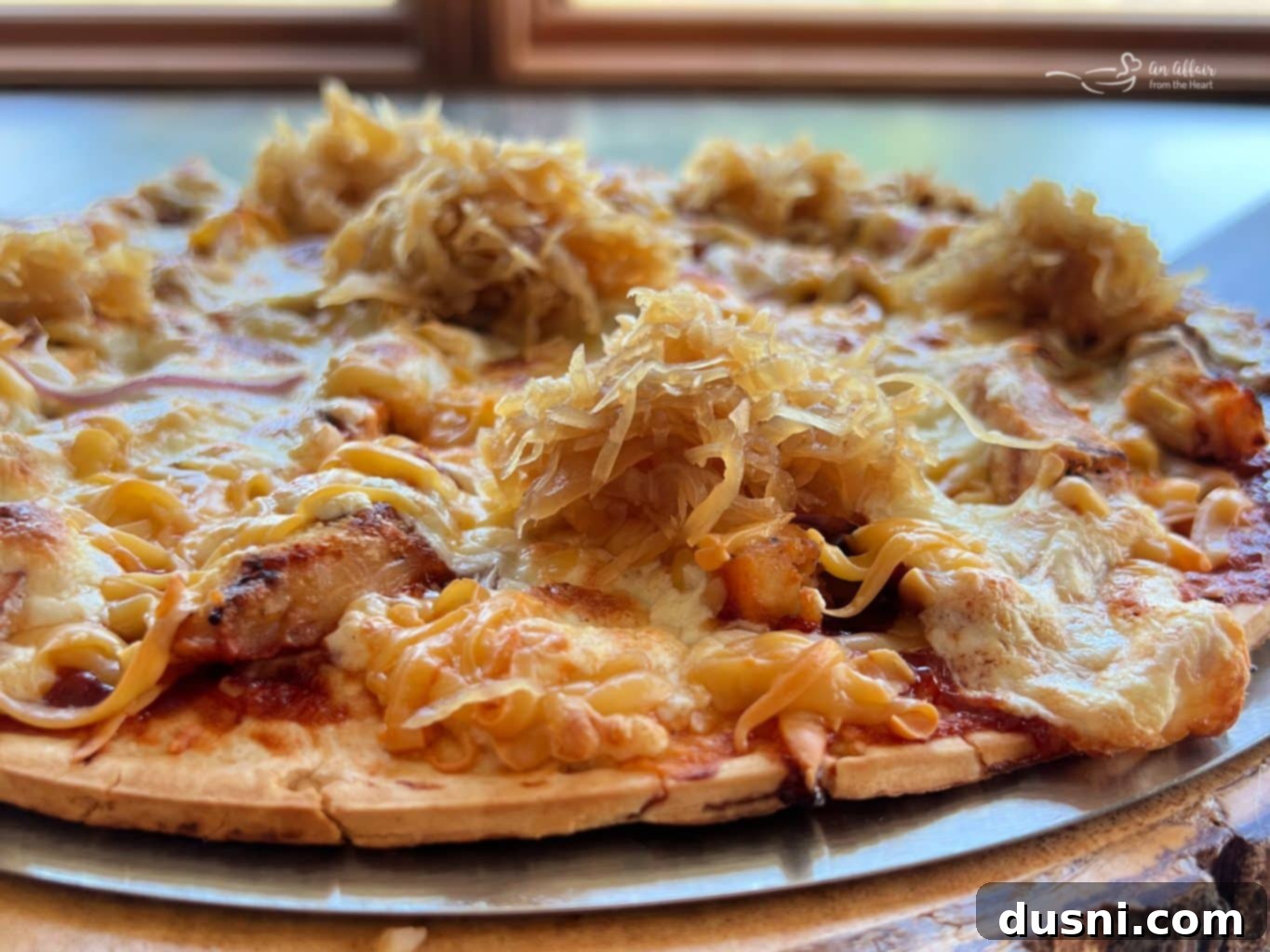 Freshly grilled BBQ chicken pizza, glistening with melted cheese, ready for the kraut topping.