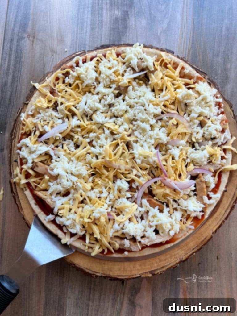 Step 3: Generously sprinkling shredded mozzarella and smoked gouda cheese over the chicken and onion.