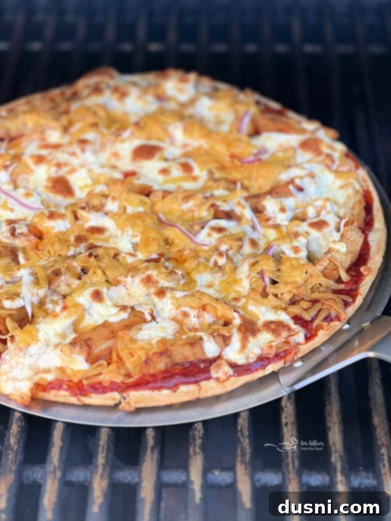 Assembled BBQ chicken pizza with kraut ready for grilling.