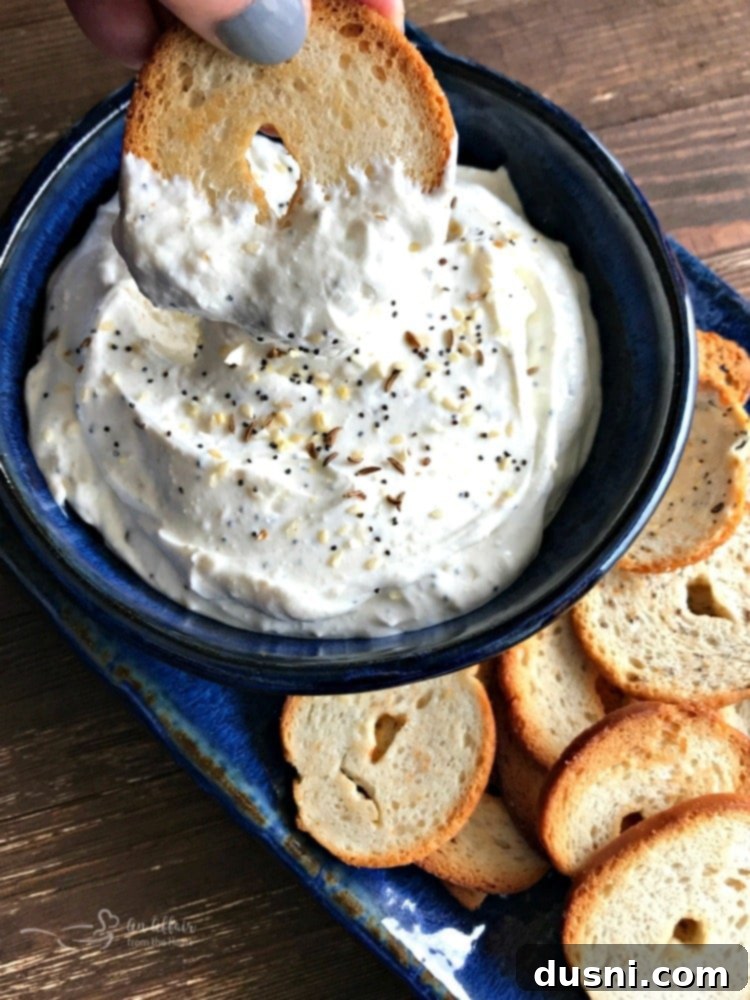 Irresistible Dips for Every Occasion 18 Everything Bagel Dip in a blue bowl, served with bagel chips.