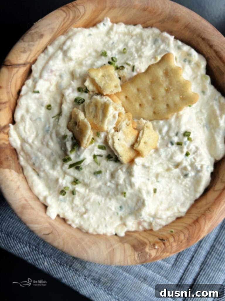Irresistible Dips for Every Occasion 23 Close up of Chicken in a Biskit Dip in a rustic wood bowl, served with crackers.