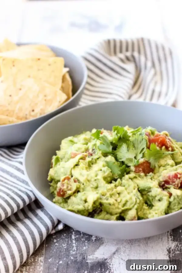 Irresistible Dips for Every Occasion 26 A bowl of fresh, creamy Guacamole with tortilla chips, garnished with cilantro.