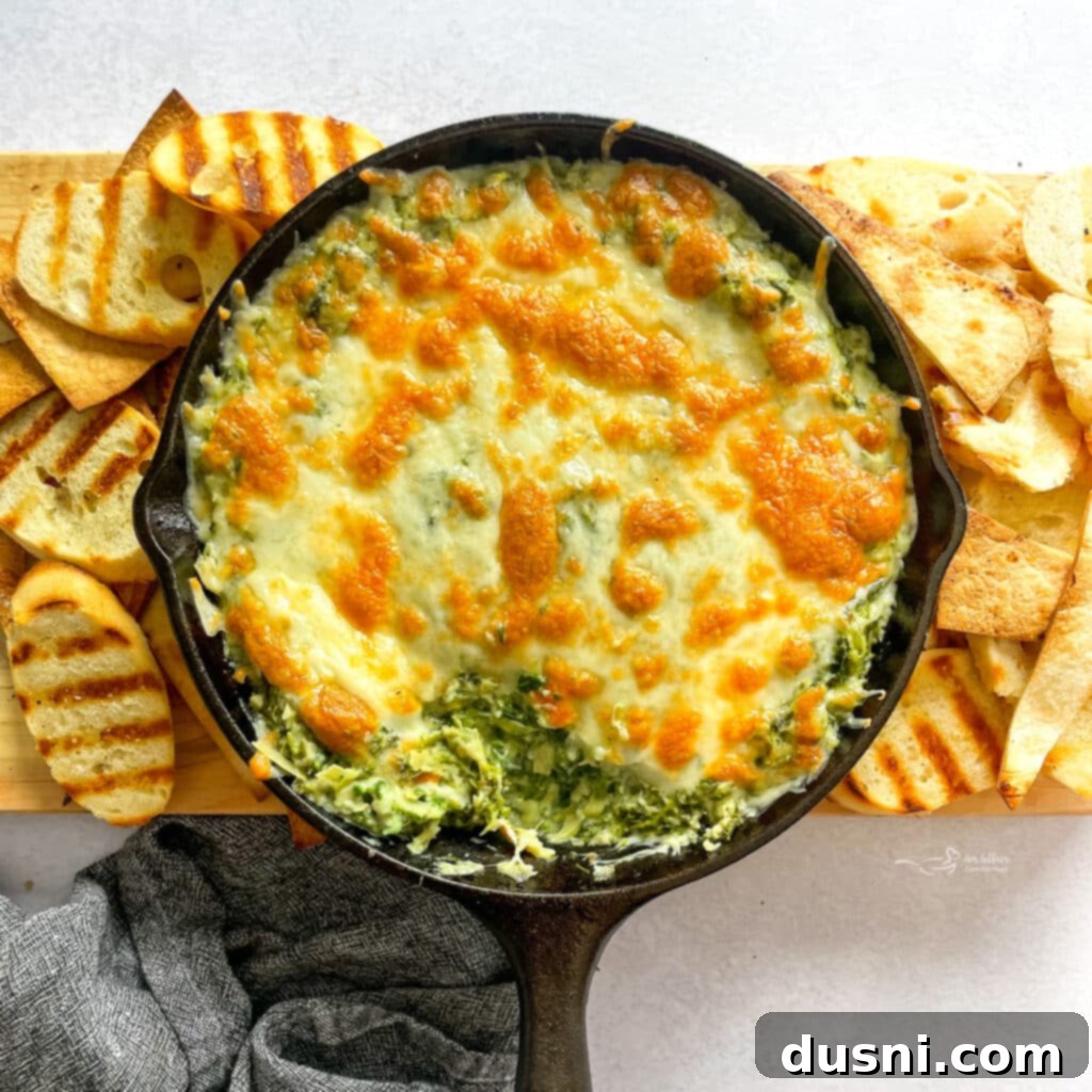 Irresistible Dips for Every Occasion 6 Creamy Spinach Artichoke Dip served warm in a skillet, surrounded by toasted bread slices.