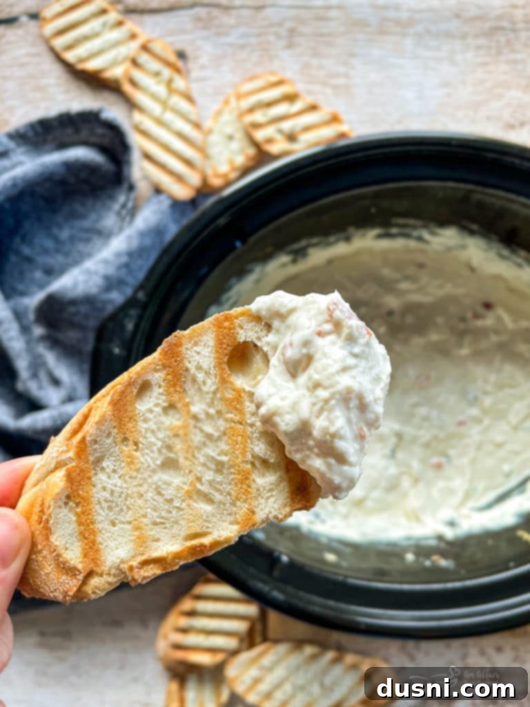 Irresistible Dips for Every Occasion 8 Close up of Slow Cooker Crab Dip on a piece of toast, garnished with fresh herbs.
