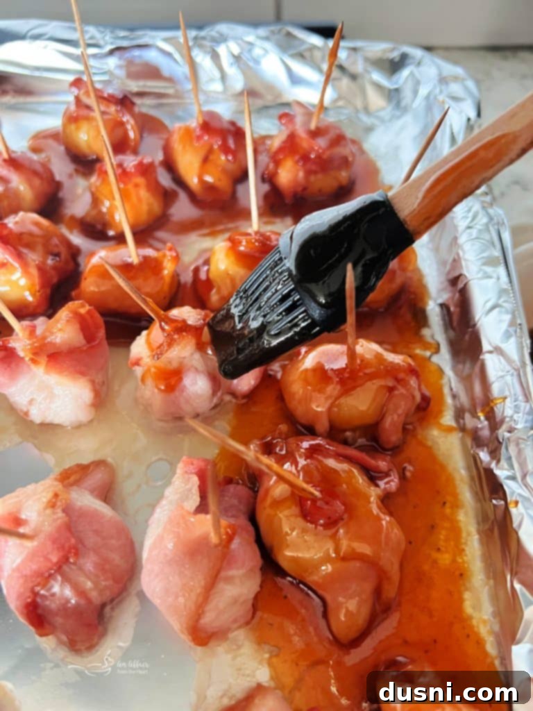 Bacon-wrapped water chestnuts arranged on a baking sheet, ready for the oven.