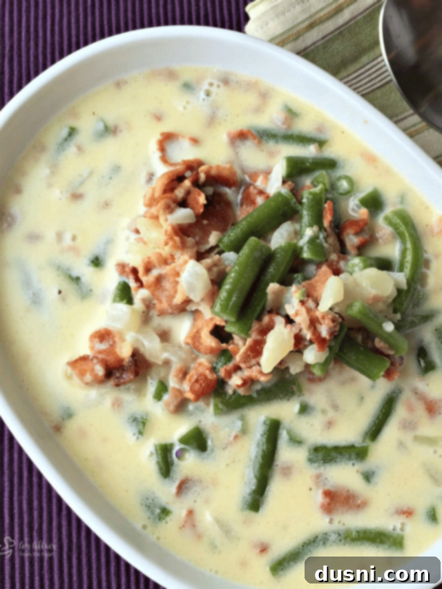 Rich and Velvety Bacon Soup 14 Close up of Potato Green Bean Bacon soup in a white serving bowl.