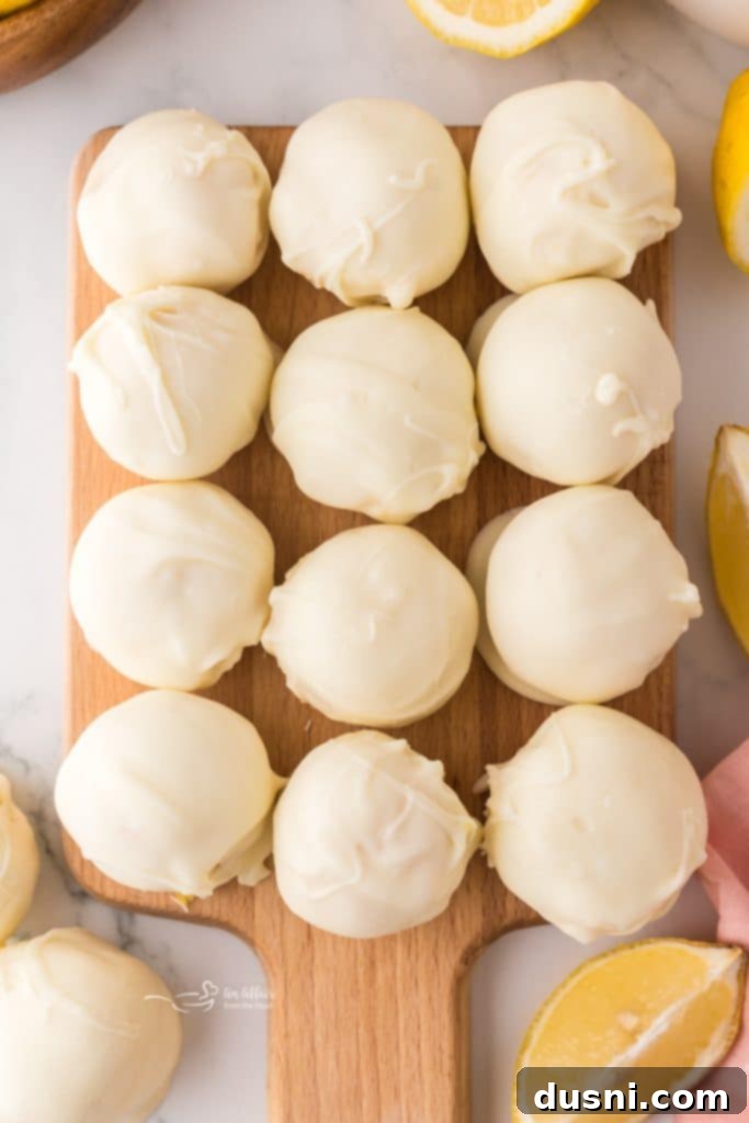 Close-up of three easy lemon truffles with a fresh lemon slice in the background.