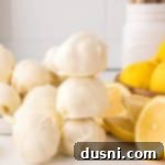 Easy Lemon Truffles stacked next to lemons in various stages of being sliced.