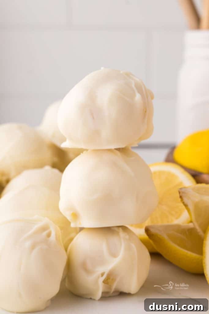 A selection of gourmet white chocolate lemon truffles on a white surface.