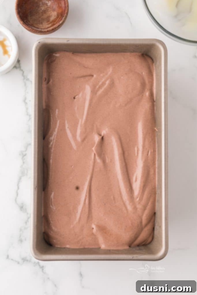 Gently folding condensed milk and malt powder into whipped cream.