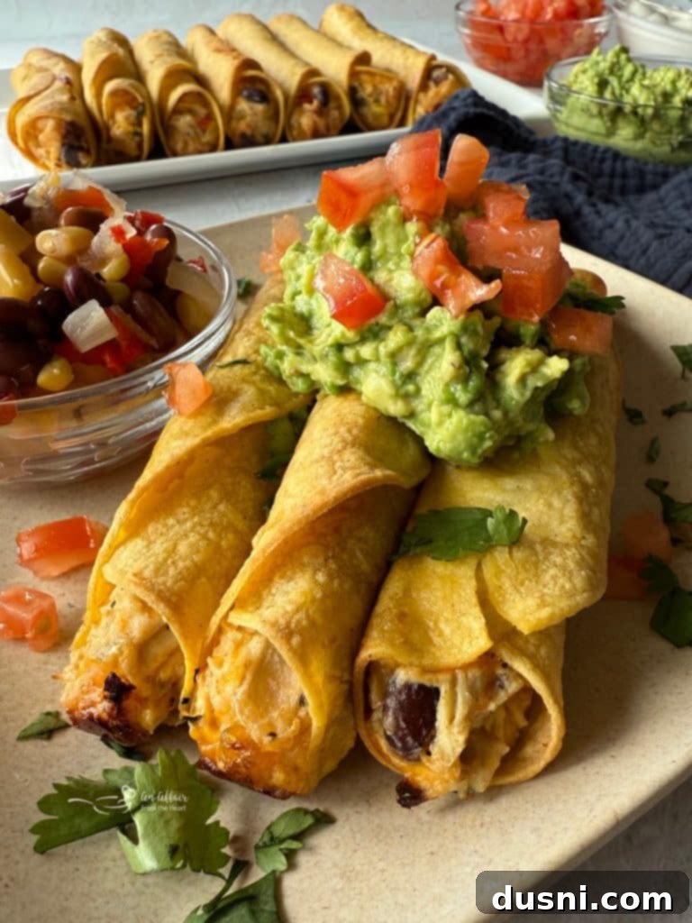 Crispy Chicken and Cowboy Caviar Taquitos piled high on a serving plate, garnished with fresh herbs.